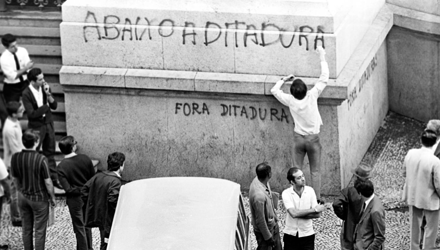 Jovem picha a fachada do Teatro Municipal do Rio durante a passeata de 26 de junho de 1968
